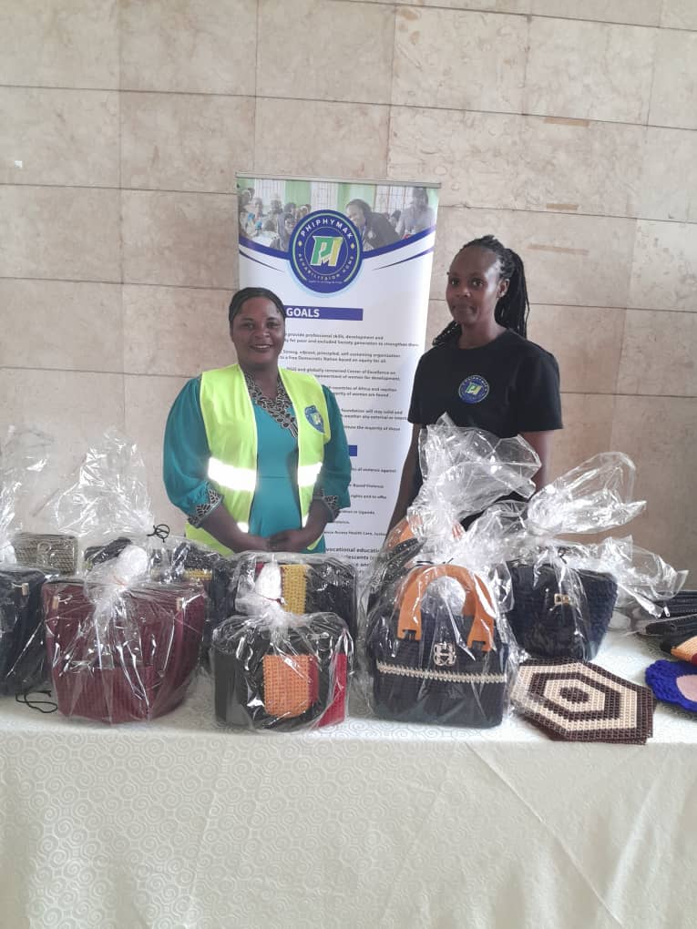 Two team members standing behind the display of handmade bags and mats