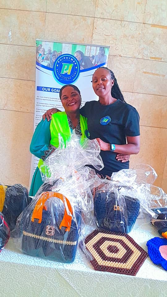 Two team members beside the stand of handmade bags and mats