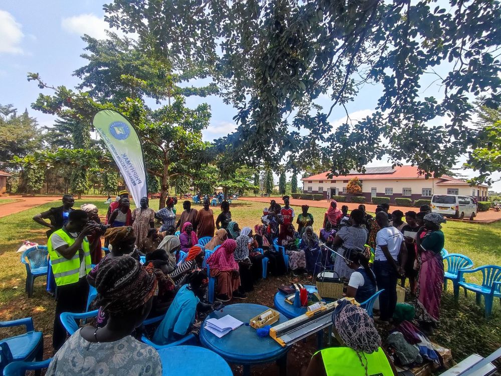 Wide view of the outreach gathering under the trees on the school grounds