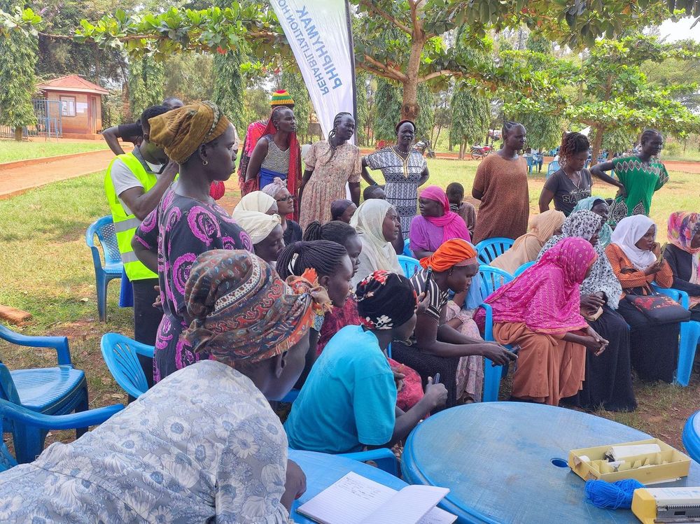 Women seated on the grass and on chairs listening during the session