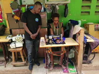 A trainee at a sewing machine in a tailoring workshop